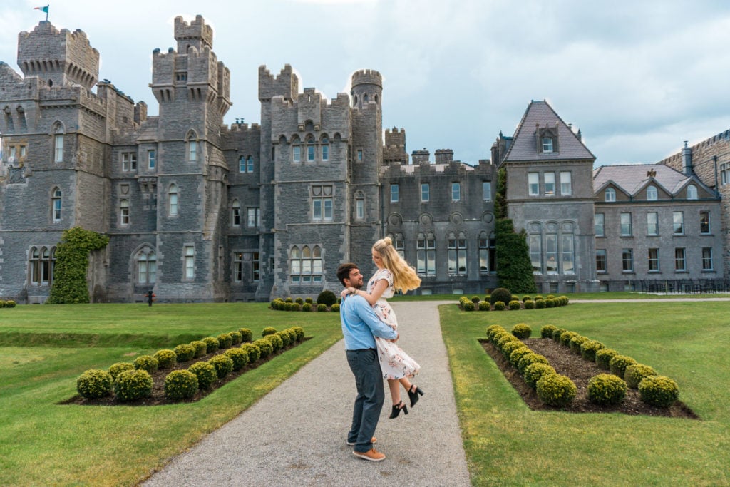 Man holding a woman and spinning together laughing in front of a castle.