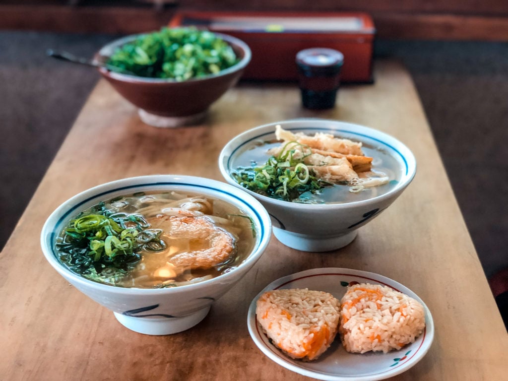 Two bowls of udon noodles and two onigiri (rice balls)