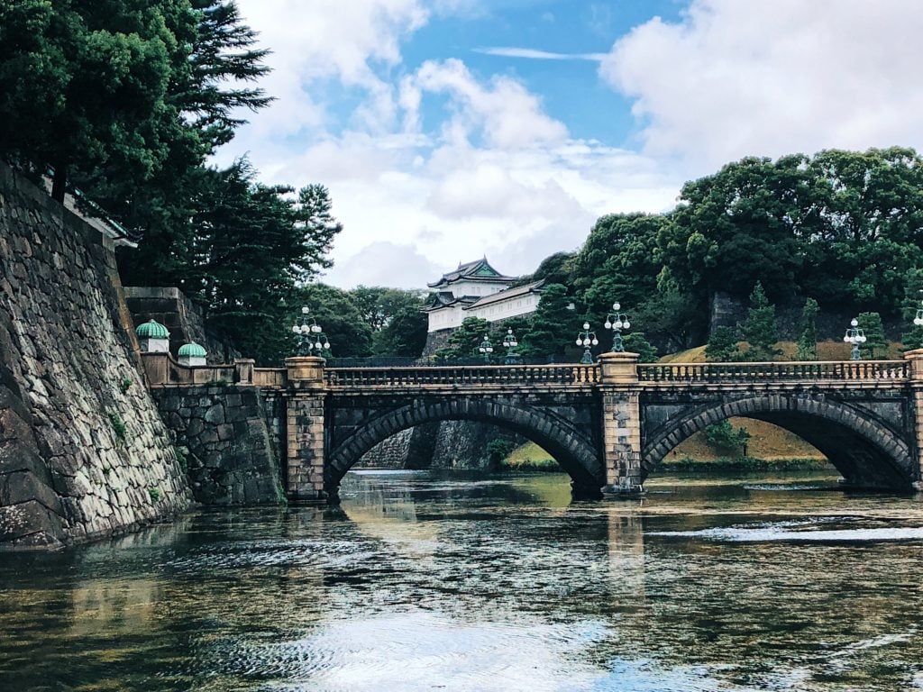 Body of water with a bridge crossing it, in the background is Tokyo Imperial Palace