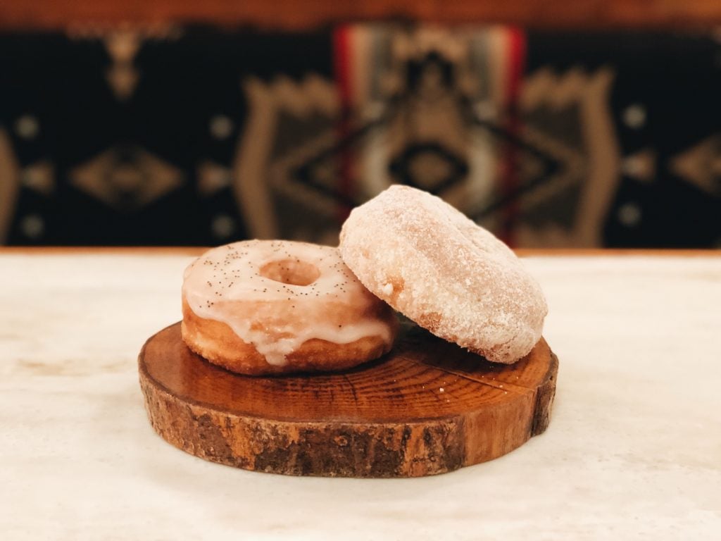 Two donuts stacked on a wood log platter.