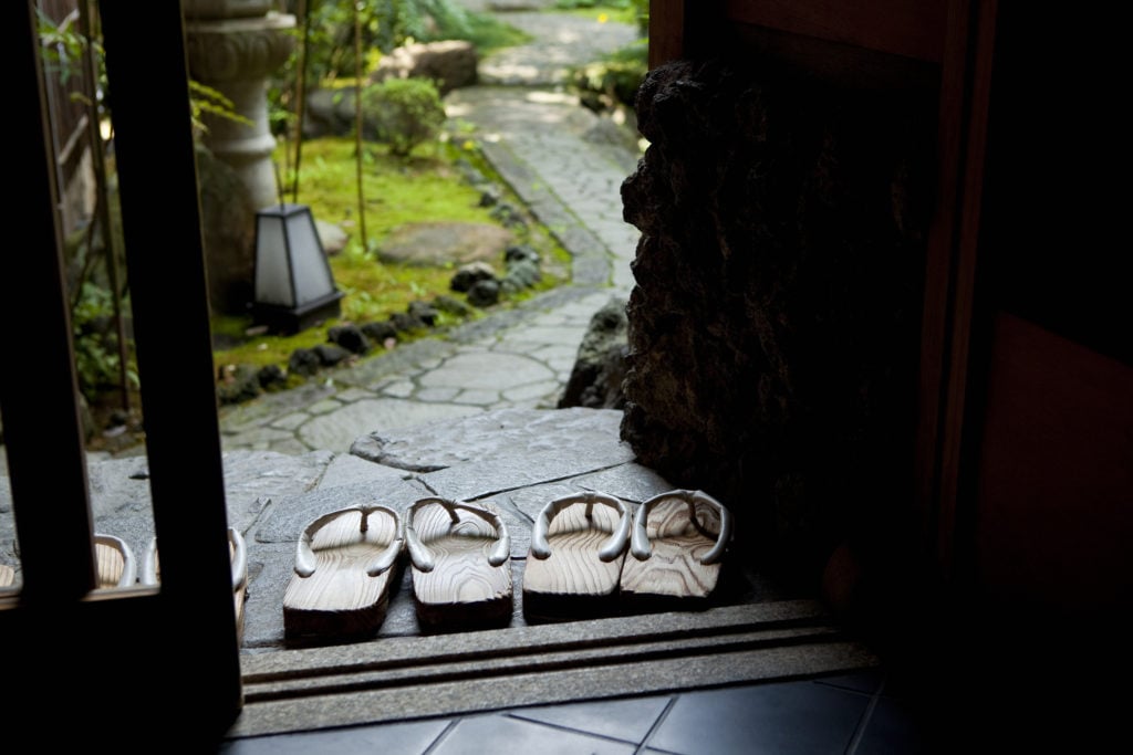 Two sets of Japanese sandals outside the door of a Japanese garden.