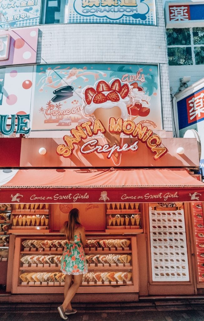 Girl standing in front of a sweet crepe stand titled "Santa Monica Crepes" in Harajuku, Japan