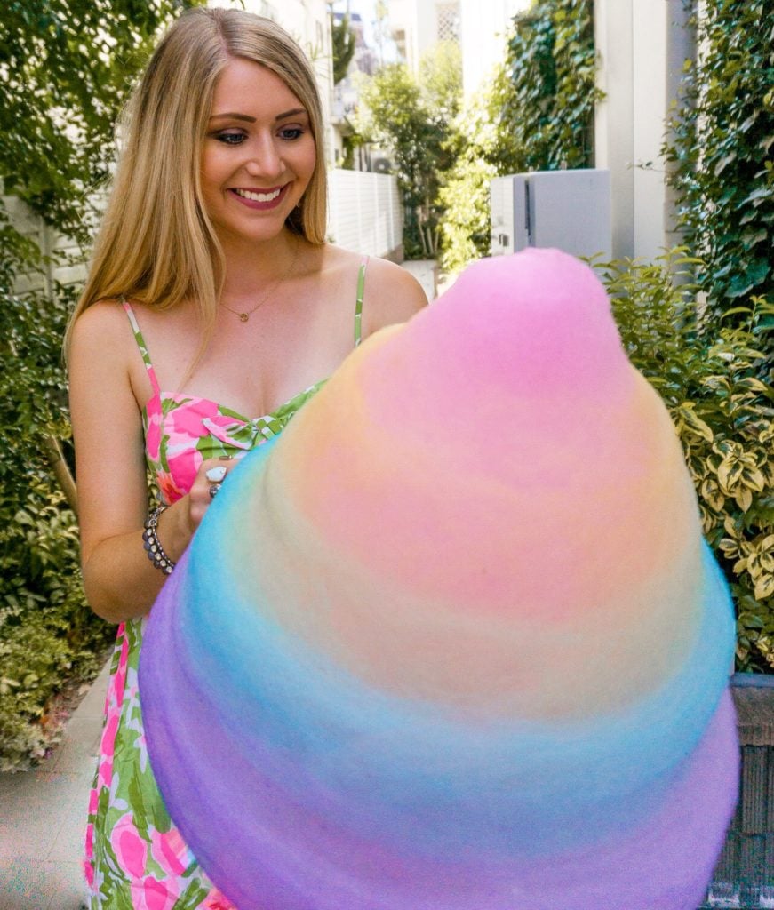 Girl smiling while holding a giant rainbow cotton candy