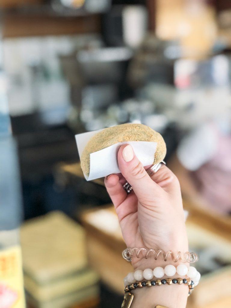 Hand holding a piece of fresh Japanese mochi with kinako (soybean powder) covering it.