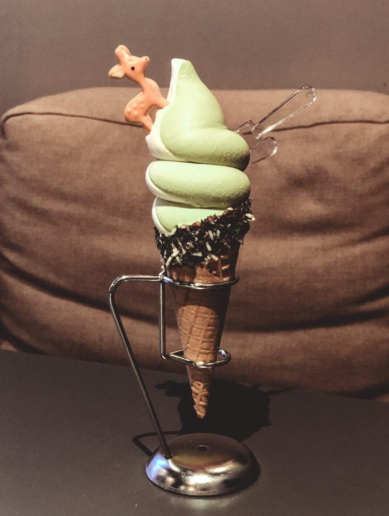 Ice cream cone with green tea and vanilla swirl ice cream and a biscuit shaped like a deer on top from Nara, Japan