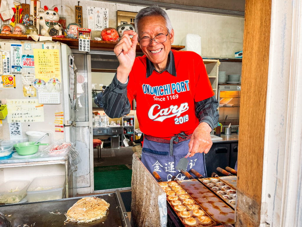 Man making takoyaki and okonomiyaki in a small shop on the Shimanami Kaido cycling trails.