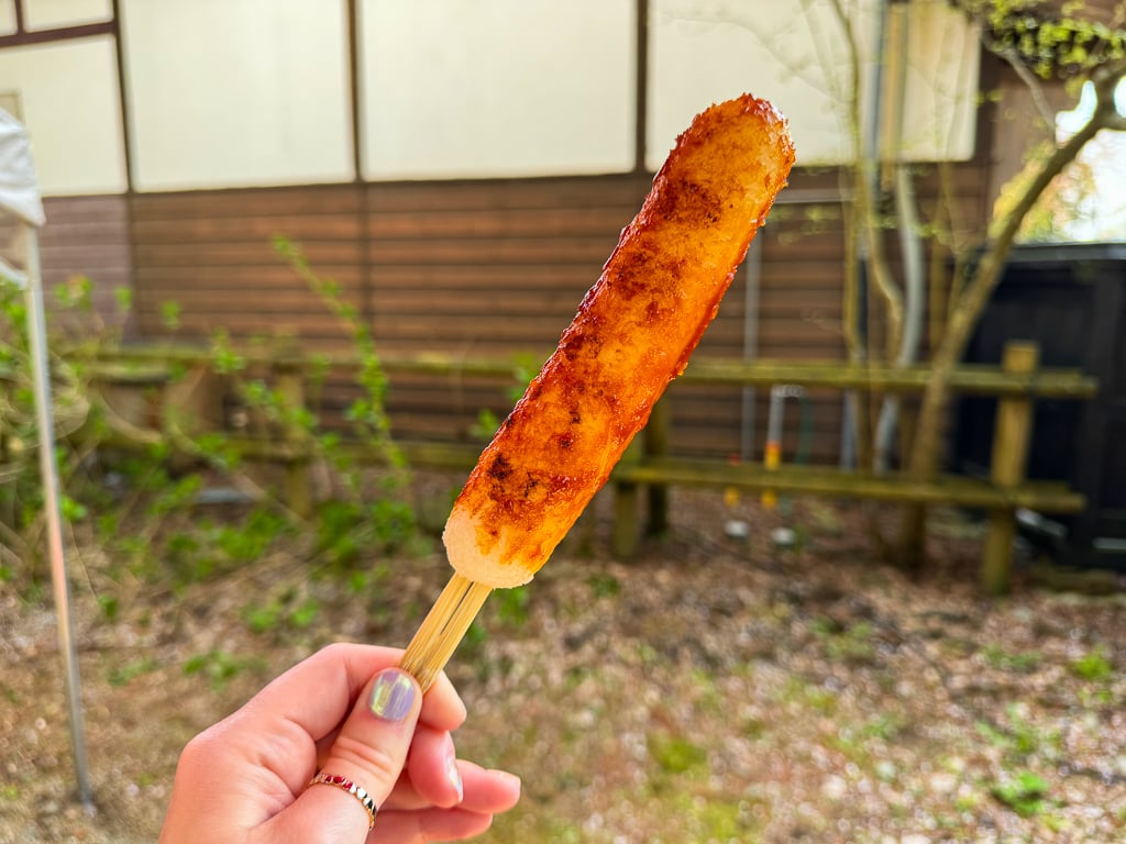 A stick/skewer of Kiritanpo, a snack made from pounded rice that is mixed with salt and formed into a skewer and grilled.