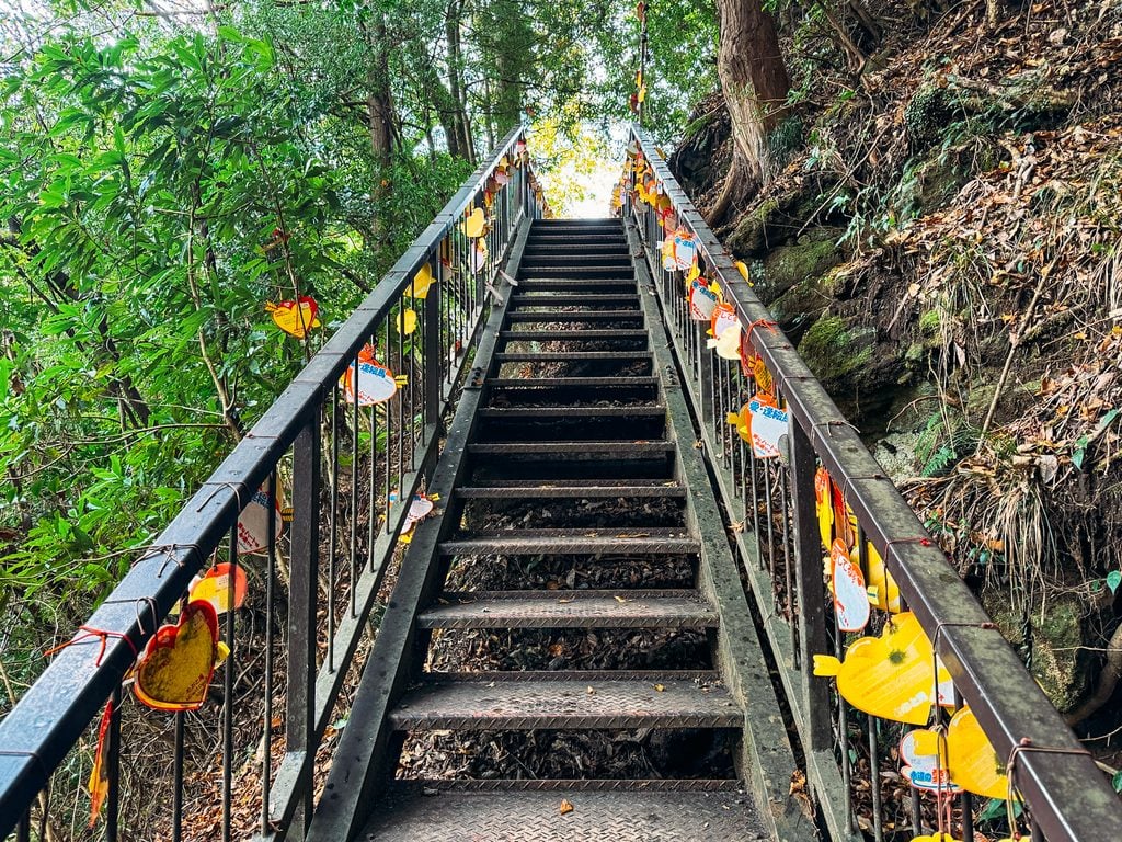 Staircase down to Meoto Falls in Kurokawa Onsen, Japan. On both sides of the railing are paper hearts tied up with string.